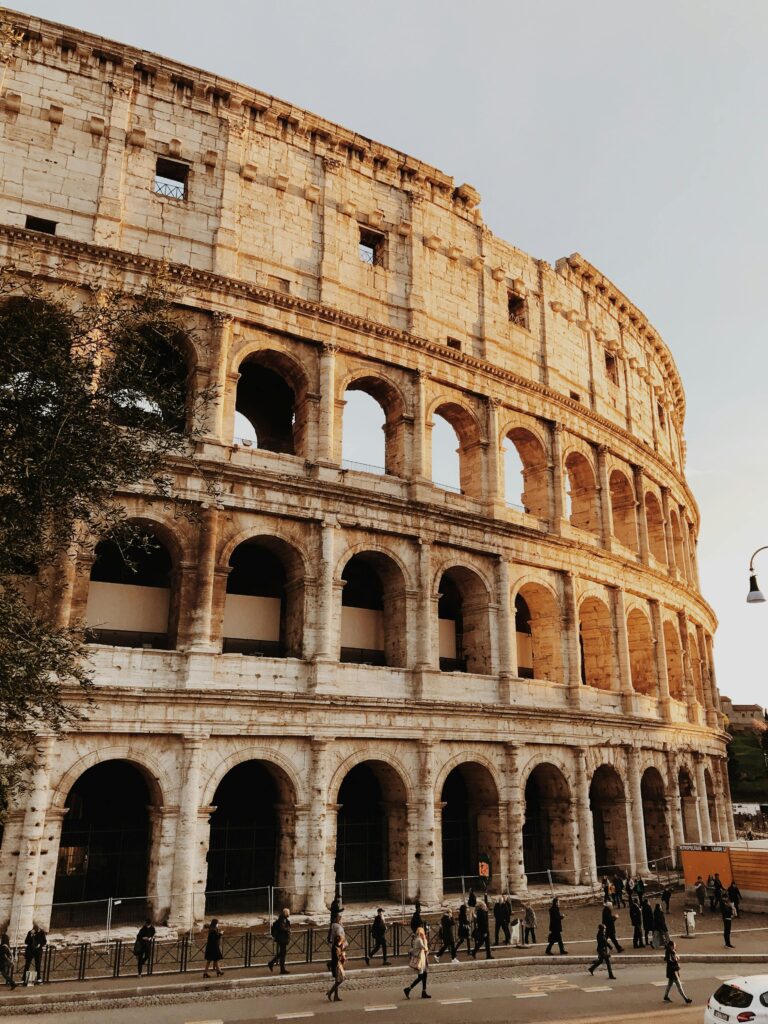 Iconic view of the Colosseum in Rome, Italy, at sunset with tourists outside.